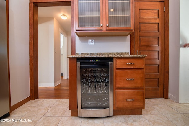 bar with wine cooler, baseboards, a bar, and light tile patterned floors