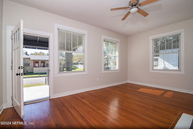 empty room with ceiling fan, baseboards, and dark wood-type flooring