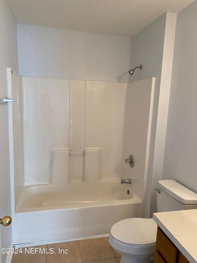 full bathroom featuring washtub / shower combination, tile patterned floors, a textured ceiling, toilet, and vanity