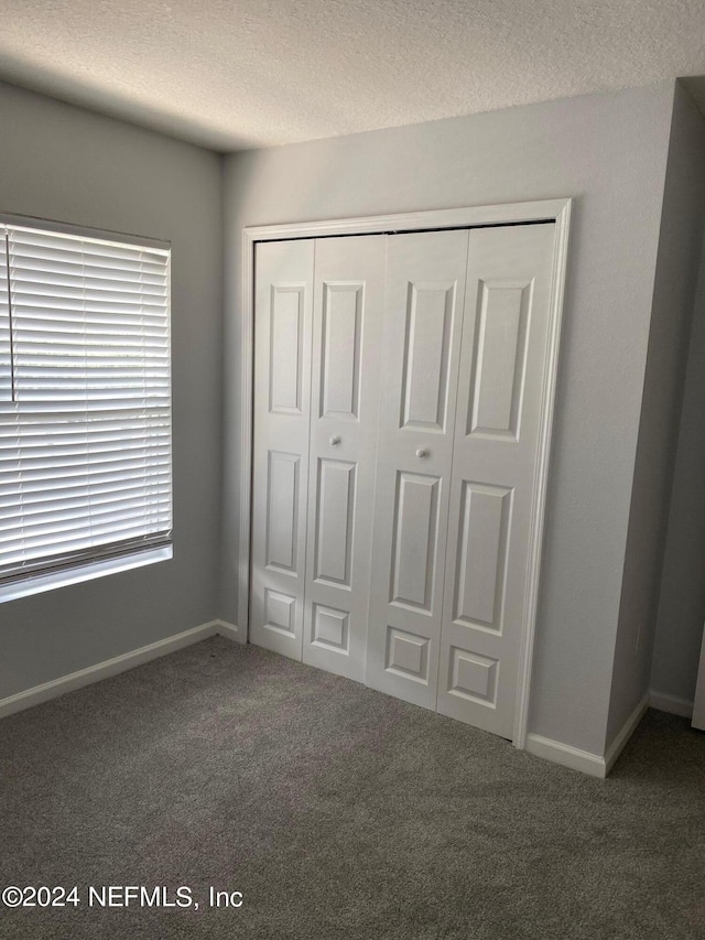 unfurnished bedroom featuring a closet, carpet, and a textured ceiling