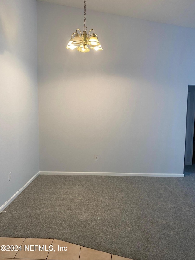 empty room featuring carpet flooring, vaulted ceiling, and an inviting chandelier