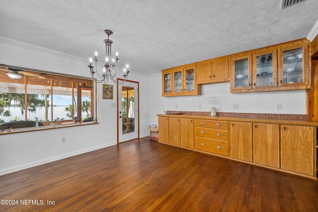 kitchen with decorative light fixtures, ceiling fan with notable chandelier, crown molding, dark wood-type flooring, and a textured ceiling