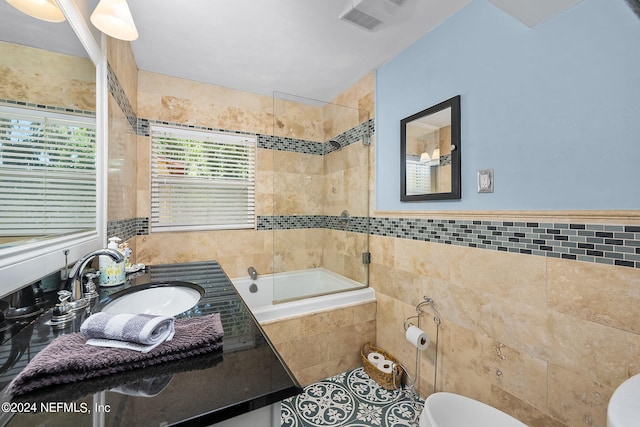 full bathroom with tile walls, large vanity, enclosed tub / shower combo, and toilet