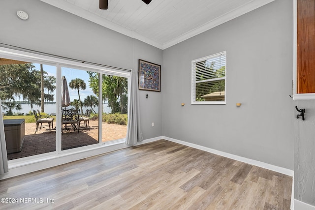 empty room with a healthy amount of sunlight, ceiling fan, light hardwood / wood-style floors, and crown molding