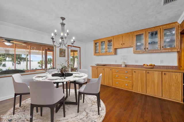 dining space featuring a textured ceiling, ceiling fan with notable chandelier, dark hardwood / wood-style flooring, and crown molding