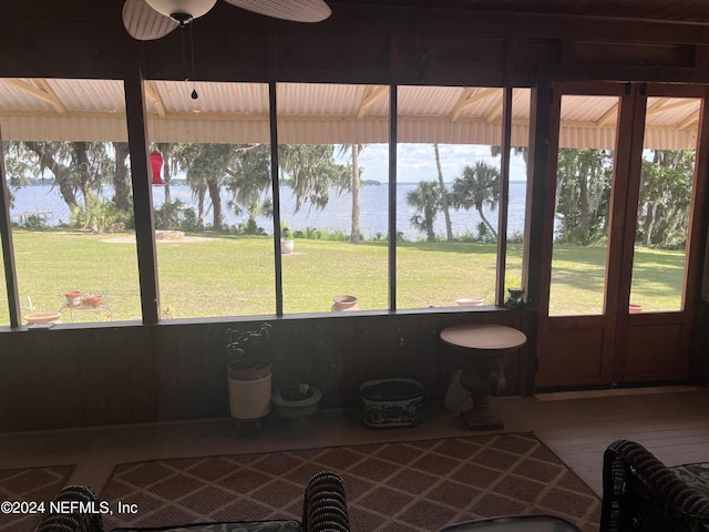 sunroom / solarium featuring plenty of natural light, ceiling fan, and a water view