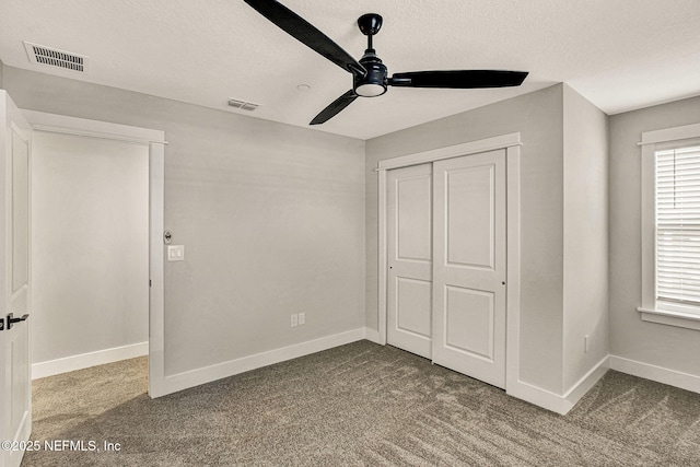 unfurnished bedroom featuring ceiling fan, carpet floors, a closet, and a textured ceiling