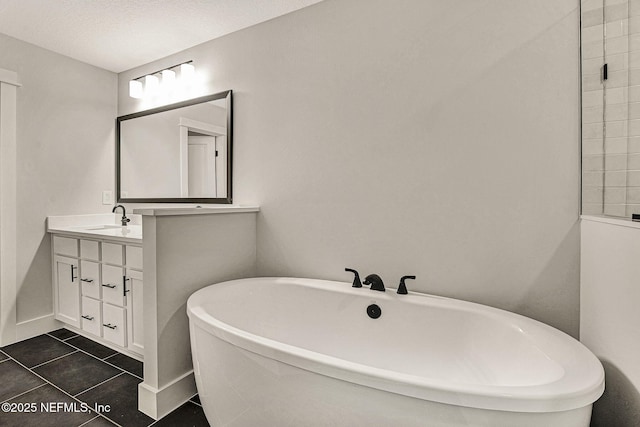 bathroom featuring tile patterned floors, vanity, a textured ceiling, and a tub