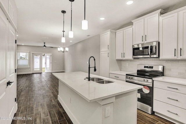 kitchen featuring sink, an island with sink, pendant lighting, stainless steel appliances, and white cabinets