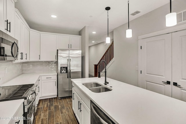 kitchen with white cabinetry, appliances with stainless steel finishes, decorative light fixtures, and sink