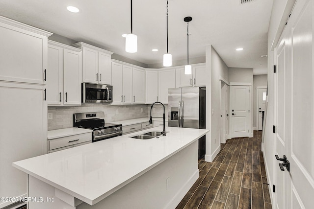 kitchen featuring decorative light fixtures, an island with sink, sink, white cabinets, and stainless steel appliances