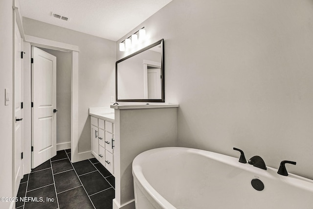 bathroom with tile patterned floors, vanity, a textured ceiling, and a washtub