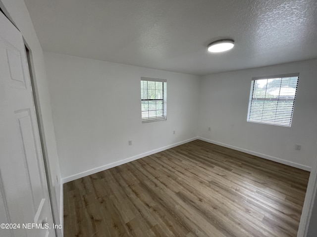 empty room featuring wood-type flooring, a healthy amount of sunlight, and a textured ceiling