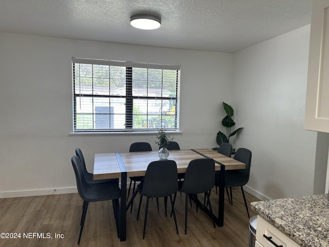 dining space with light hardwood / wood-style floors and a textured ceiling