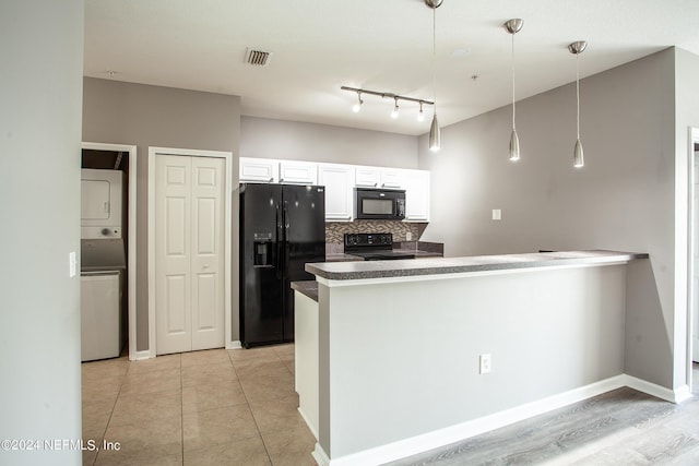 kitchen featuring decorative backsplash, black appliances, decorative light fixtures, stacked washer and clothes dryer, and white cabinetry