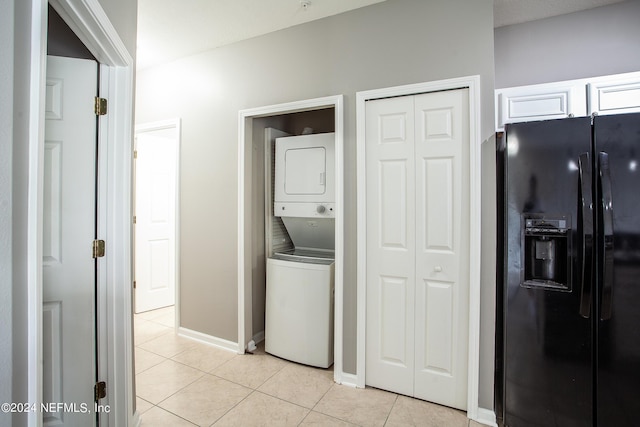 laundry area featuring stacked washer and dryer and light tile patterned floors