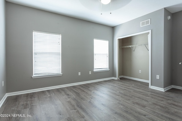 unfurnished bedroom with ceiling fan, a closet, and wood-type flooring