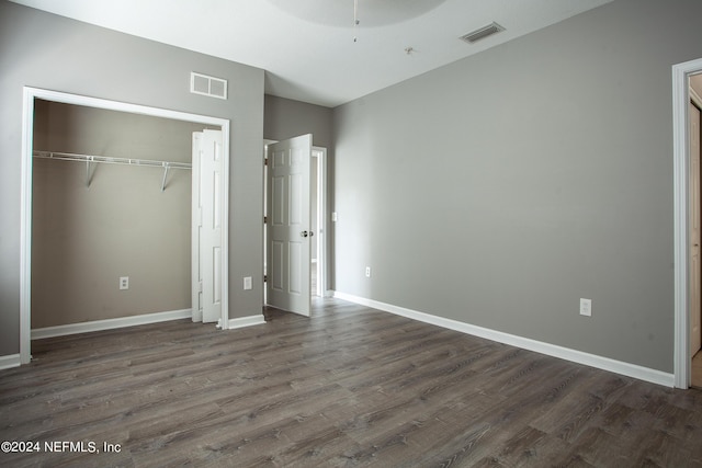 unfurnished bedroom with a closet and dark wood-type flooring