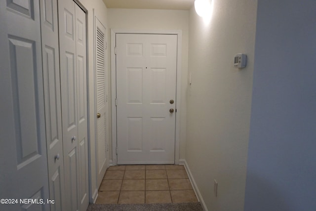 doorway with light tile patterned floors and baseboards