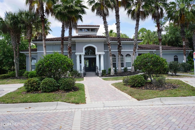 mediterranean / spanish-style home featuring stucco siding, a tiled roof, and french doors