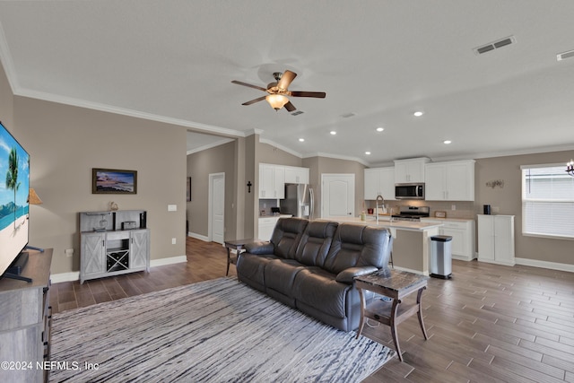 living room with ceiling fan, ornamental molding, sink, and vaulted ceiling