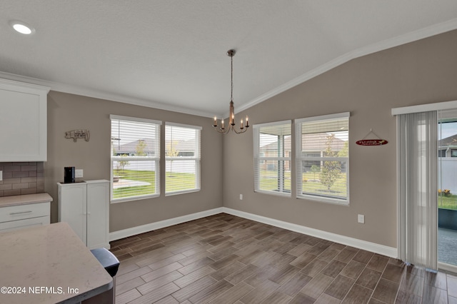 unfurnished dining area with ornamental molding, lofted ceiling, and an inviting chandelier