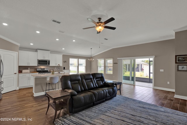 living room with lofted ceiling, crown molding, dark wood-type flooring, and ceiling fan with notable chandelier