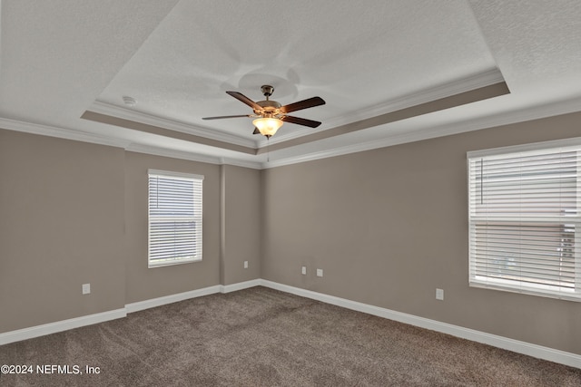 carpeted spare room with a tray ceiling, ceiling fan, and ornamental molding