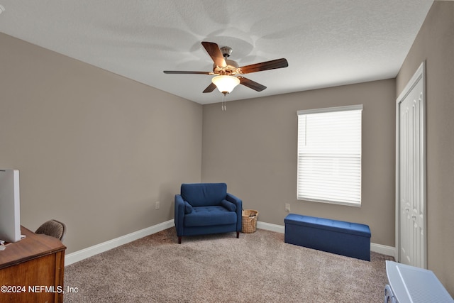 living area with carpet, a textured ceiling, and ceiling fan