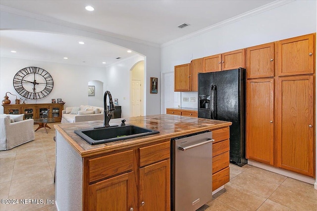 kitchen with black fridge, a kitchen island with sink, crown molding, sink, and light tile patterned floors