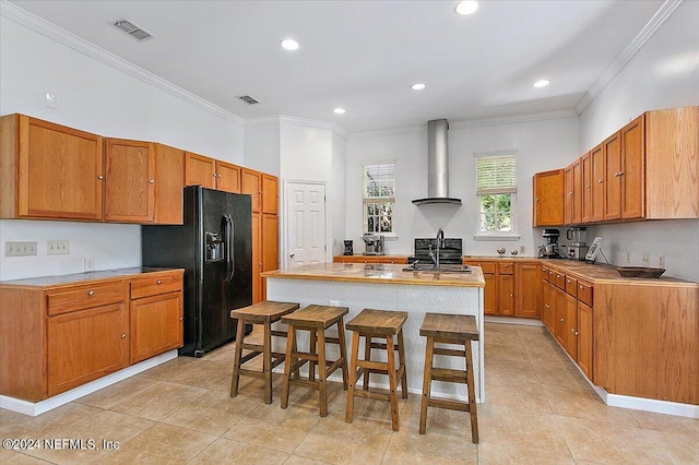 kitchen with a center island, sink, range hood, a breakfast bar area, and black fridge with ice dispenser