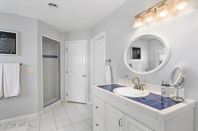 bathroom featuring tile patterned floors, vanity, and a tile shower