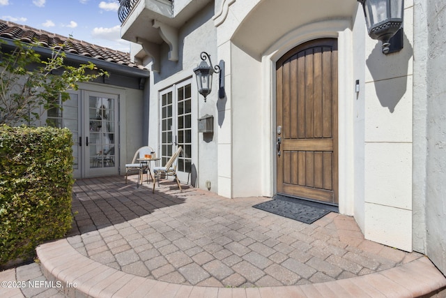 doorway to property featuring a patio area, french doors, a tile roof, and stucco siding