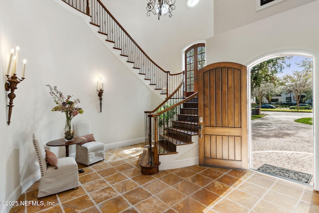 entryway with baseboards, a high ceiling, and stairs