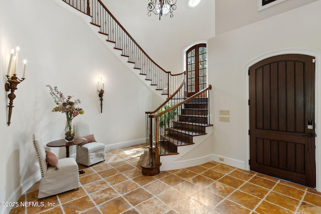 entrance foyer with arched walkways, baseboards, a high ceiling, and stairs