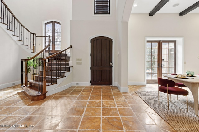 entryway with french doors, baseboards, a towering ceiling, and beam ceiling