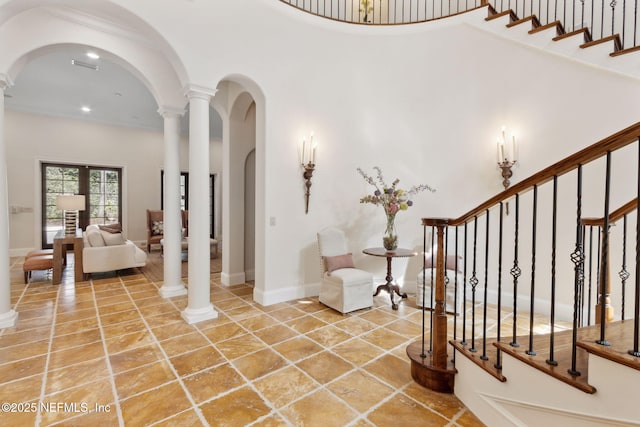 entryway with arched walkways, a high ceiling, ornate columns, and stairs