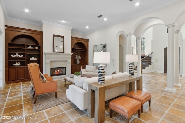 living room with crown molding, a lit fireplace, built in features, and ornate columns