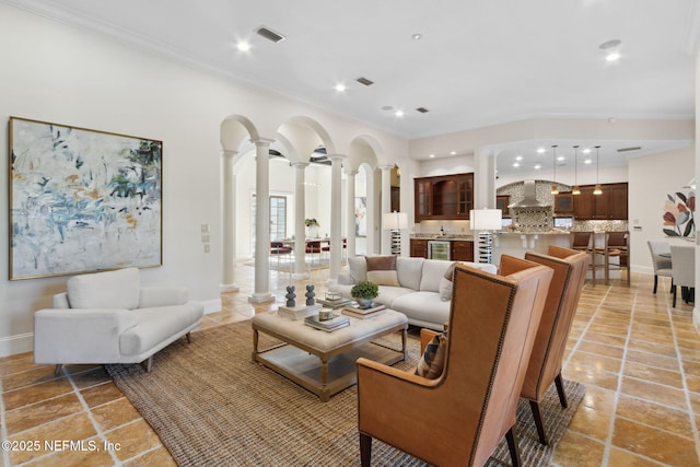 living room with arched walkways, visible vents, baseboards, ornamental molding, and ornate columns