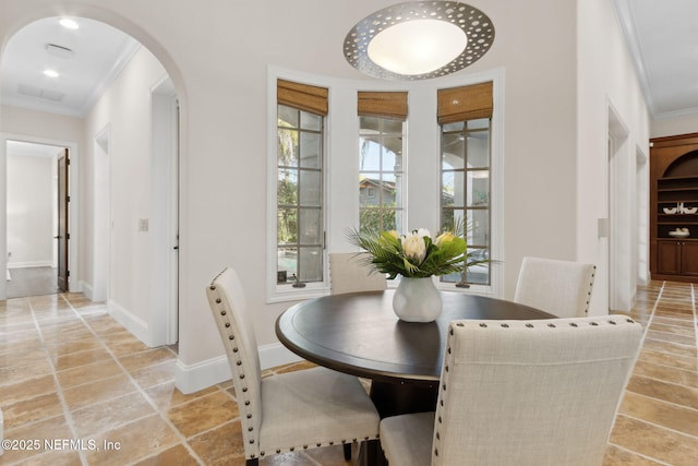 dining area featuring ornamental molding, arched walkways, visible vents, and baseboards