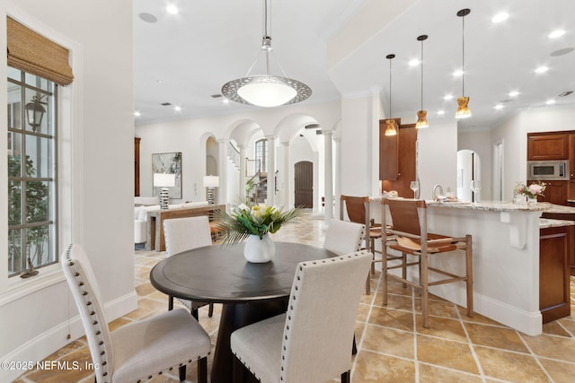 dining room featuring crown molding, arched walkways, plenty of natural light, and ornate columns