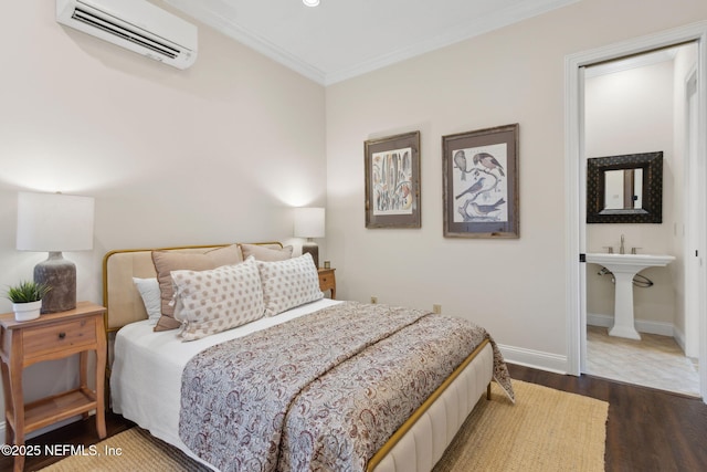 bedroom with connected bathroom, baseboards, a wall mounted AC, dark wood-style floors, and crown molding