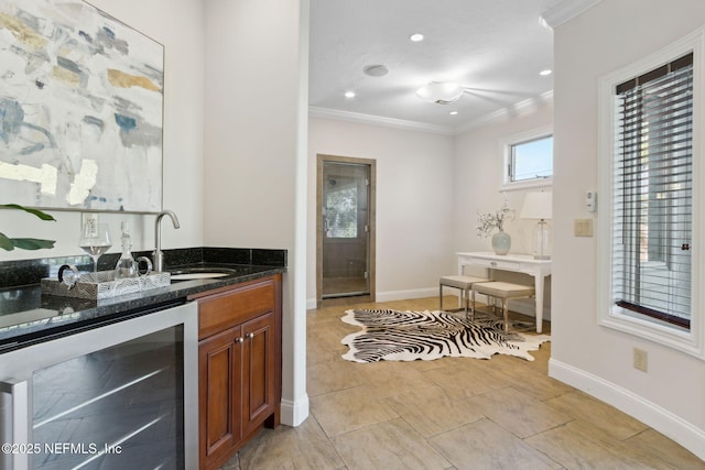 bar with ornamental molding, a sink, wet bar, beverage cooler, and baseboards