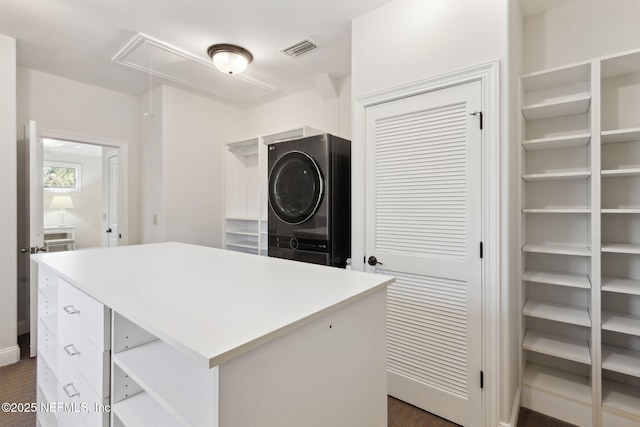 walk in closet with attic access, stacked washer and clothes dryer, and visible vents