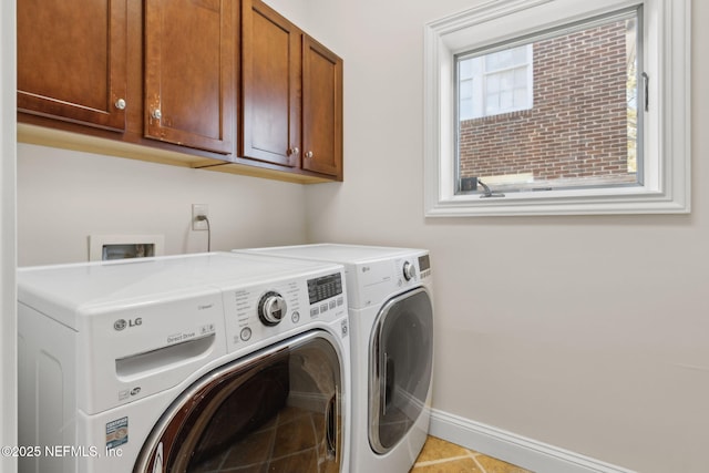 clothes washing area with washing machine and clothes dryer, cabinet space, and baseboards