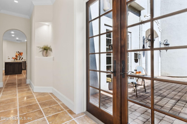 entryway featuring baseboards, arched walkways, ornamental molding, tile patterned floors, and french doors