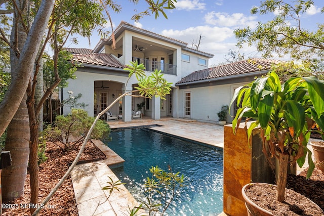 back of house with a patio, stucco siding, a ceiling fan, a balcony, and a tiled roof