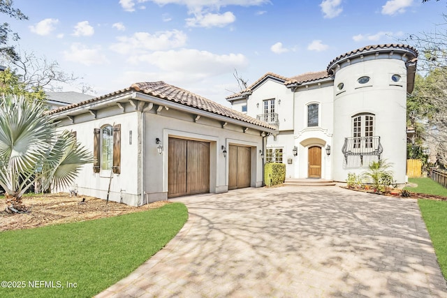 mediterranean / spanish home featuring an attached garage, driveway, a tile roof, and stucco siding