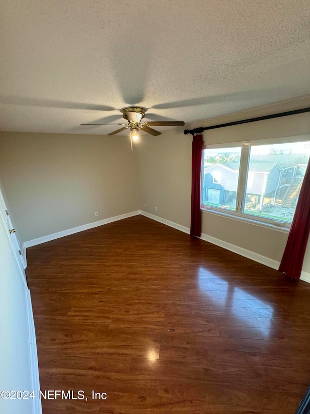 spare room with a textured ceiling, dark wood-type flooring, and ceiling fan