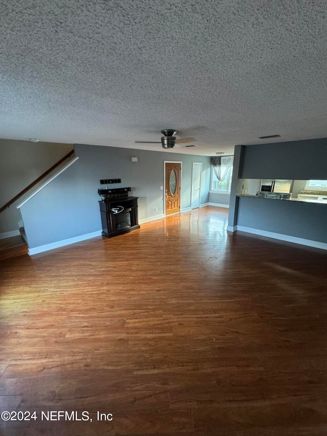 unfurnished living room with hardwood / wood-style flooring, ceiling fan, and a textured ceiling